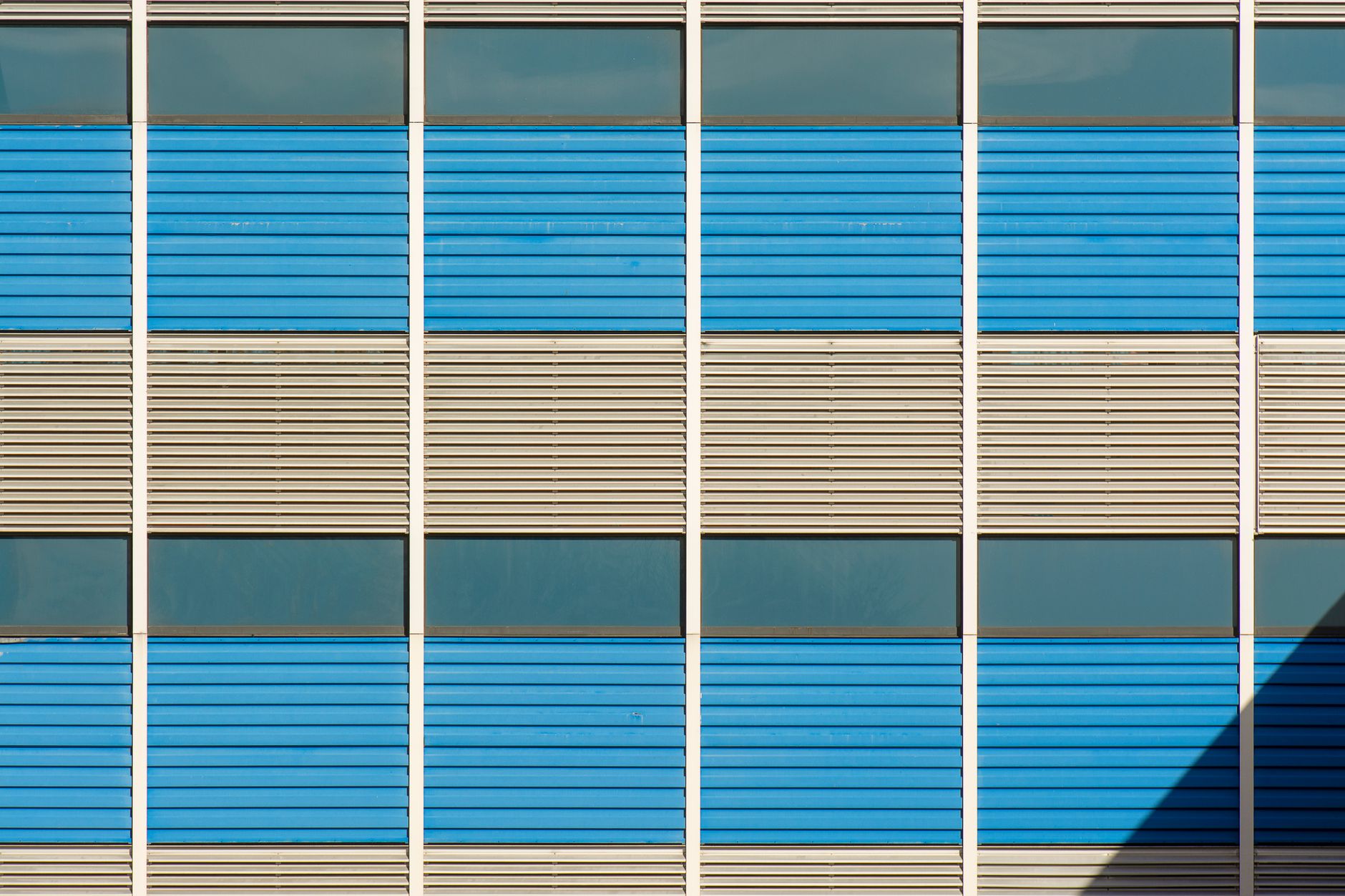 Close-up of a modern facade with blue and beige panels in a geometric pattern.
