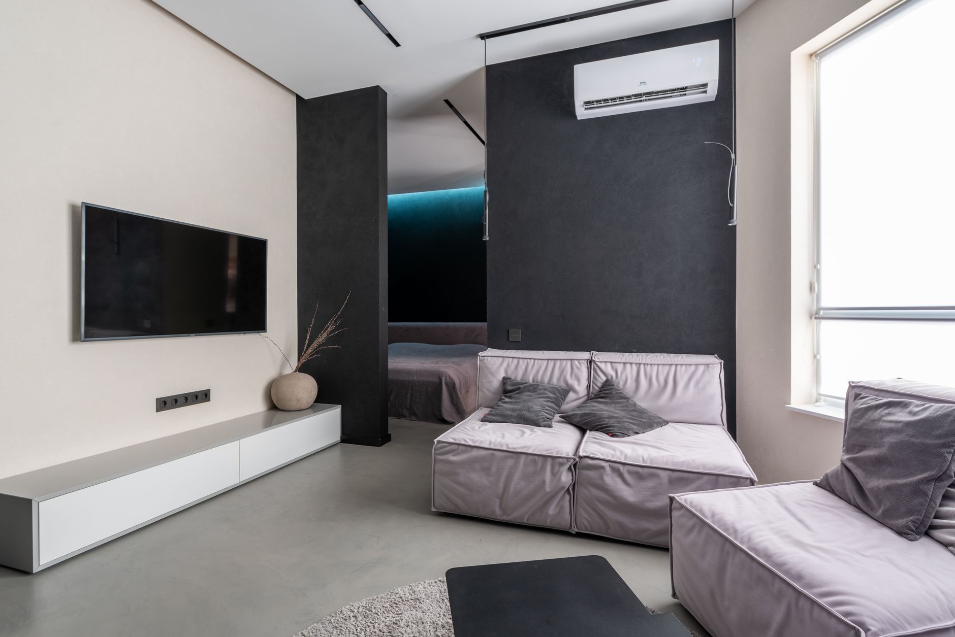 A spacious modern living room with soft sofas and a low media wall.