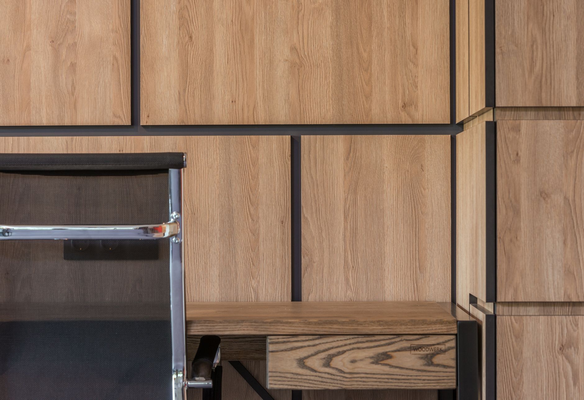 A chair at a desk beside a tall wooden cabinet in a quiet working room.