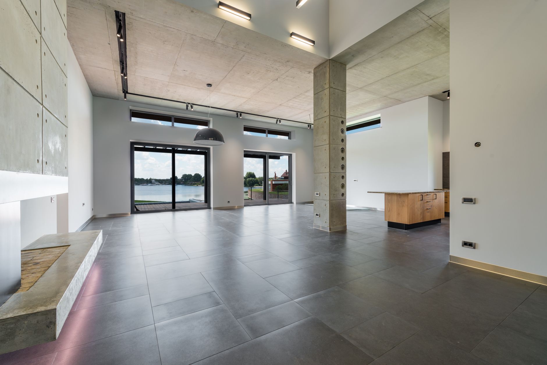 Interior of a minimalist house with wooden furniture and panoramic windows over the water.